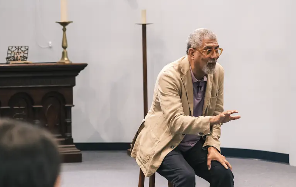 Man sitting and leaning in to talk to a group
