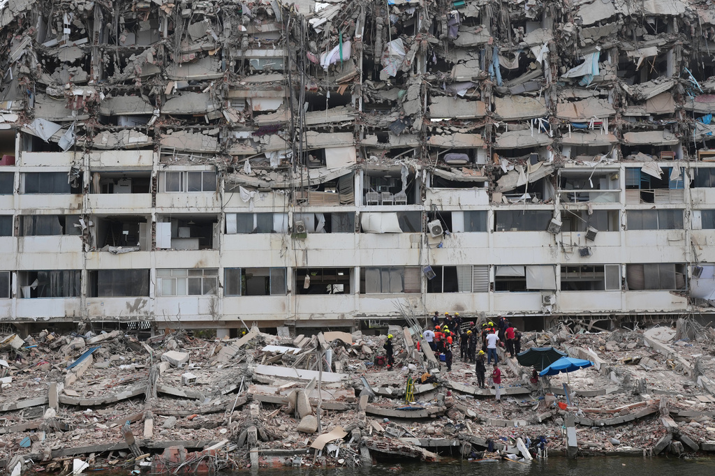 Rescue workers search through the rubble of a building that collapsed when earthquakes struck La Guaira, Venezuela