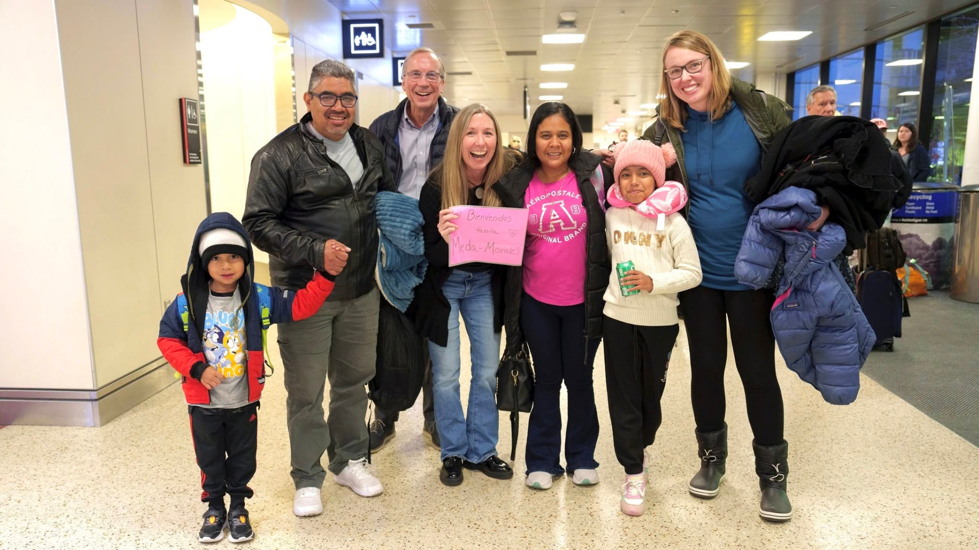 A Neighborhood Support Team greets a refugee family at the airport.