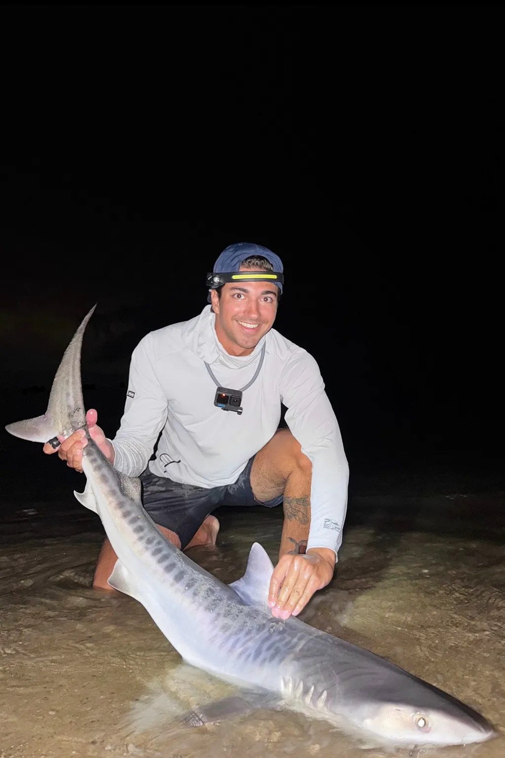 Nate Rouette holding a young tiger shark that they caught off Falmouth, Mass.
