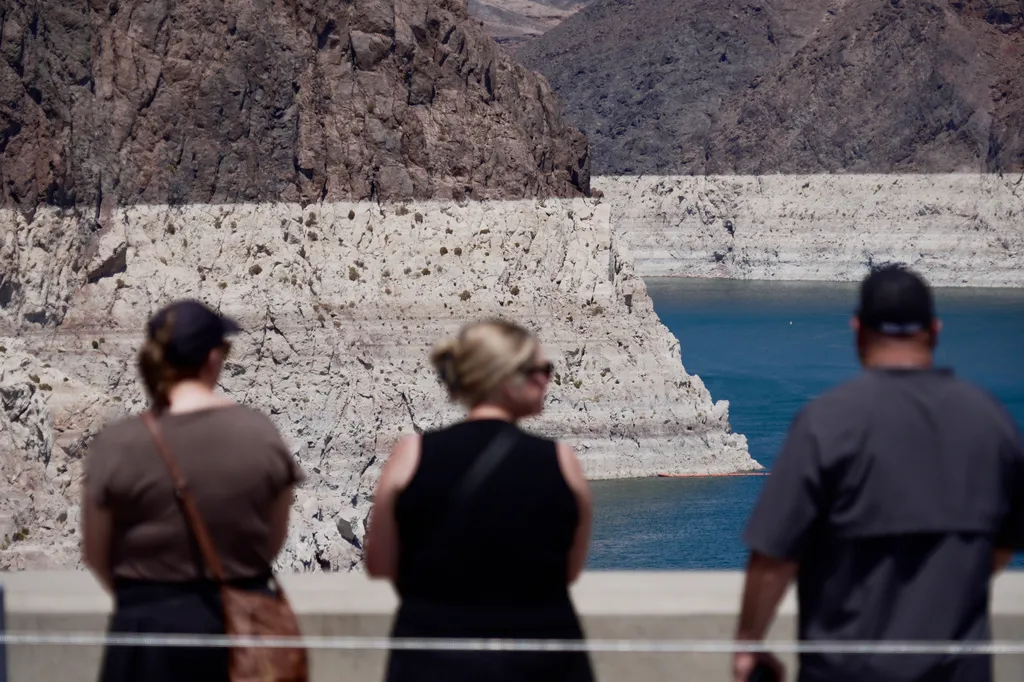 Tourists on the Hoover Dam look out at the bathtub ring of minerals that shows the former water levels of Lake Mead near Boulder City, Nev.