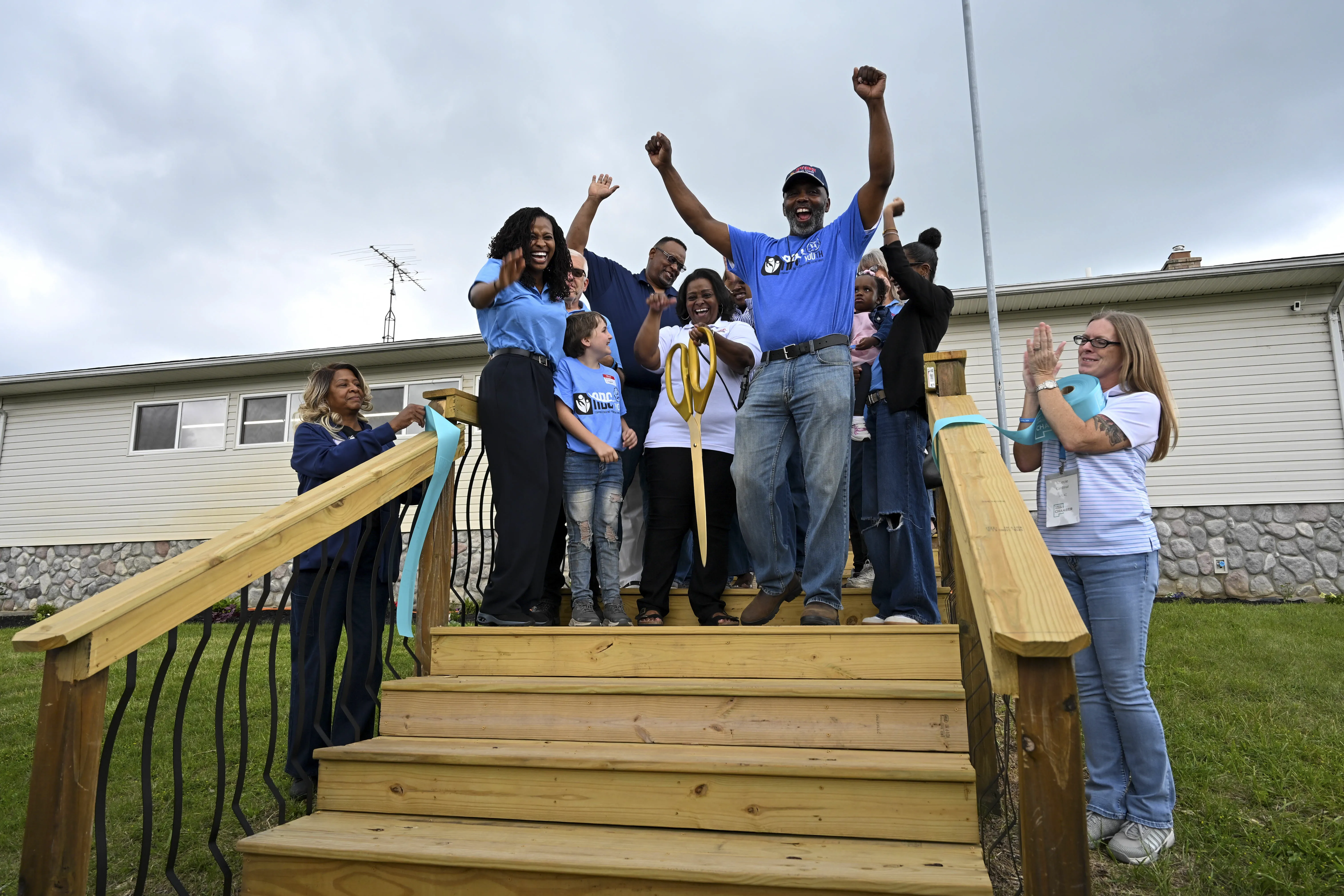 Derrick Watkins raises his hands to the sky with other ABC Youth Volunteers At The Official Ribbon Cutting Ceremony