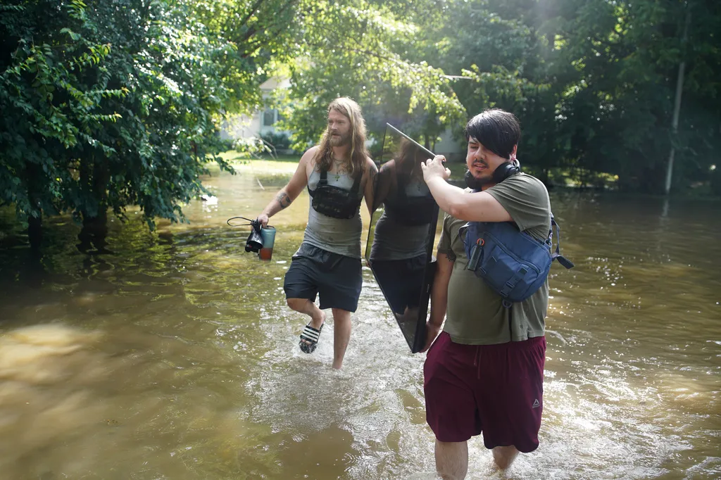 Darius Canler and Curtis Carey carry a TV from their flooded home in Indianapolis