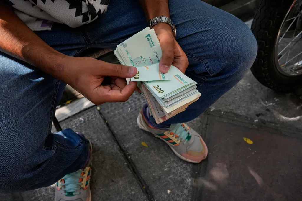 A money exchanger counts Iranian banknotes at Ferdowsi square, Tehran