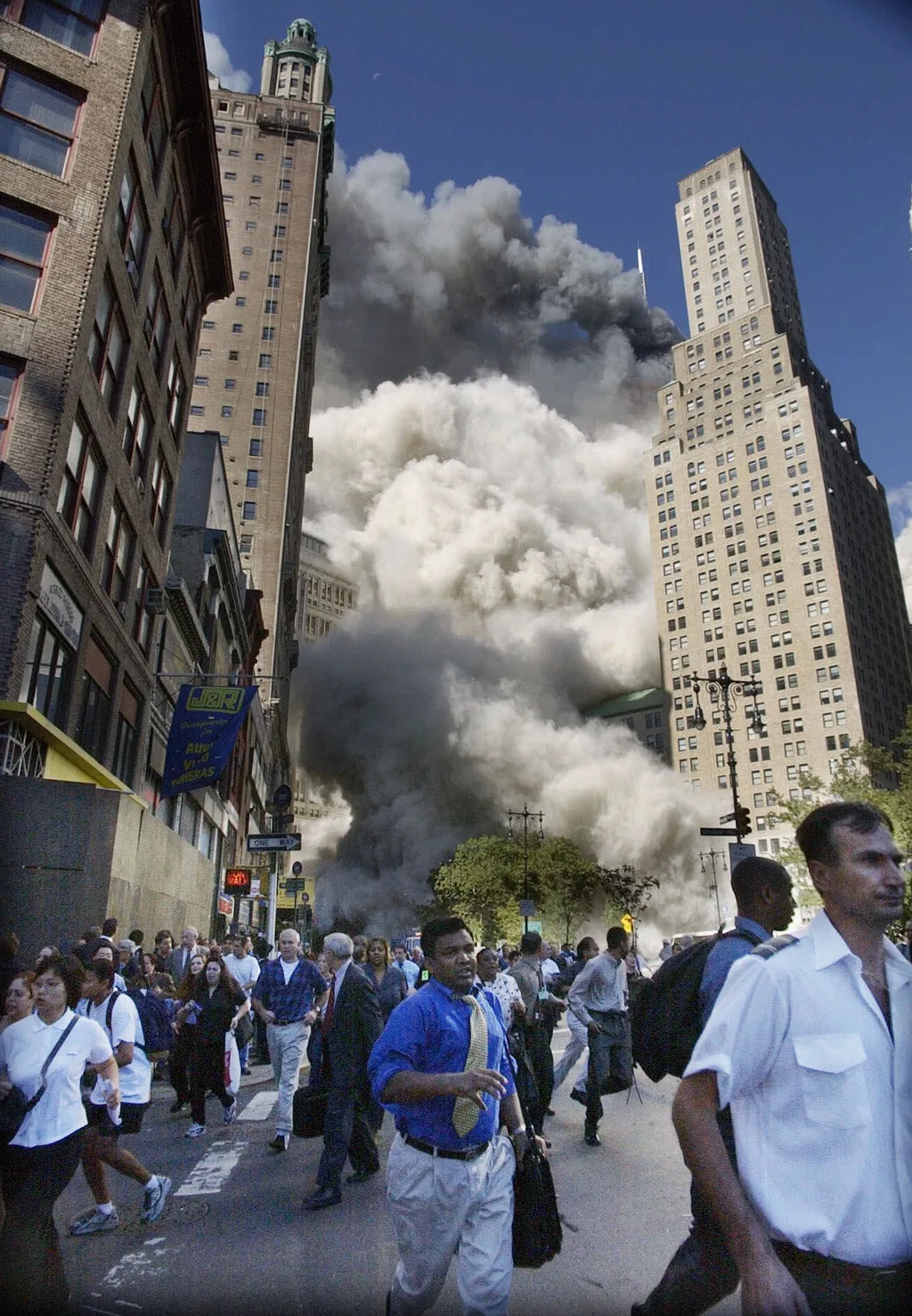 Pedestrians flee the area of the World Trade Center as the center