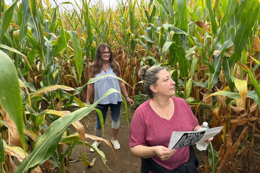 Jaime Wanzer, holding a map, and Wendy Mayerson navigate a 5-acre corn maze designed as a portrait of Dolly Parton 