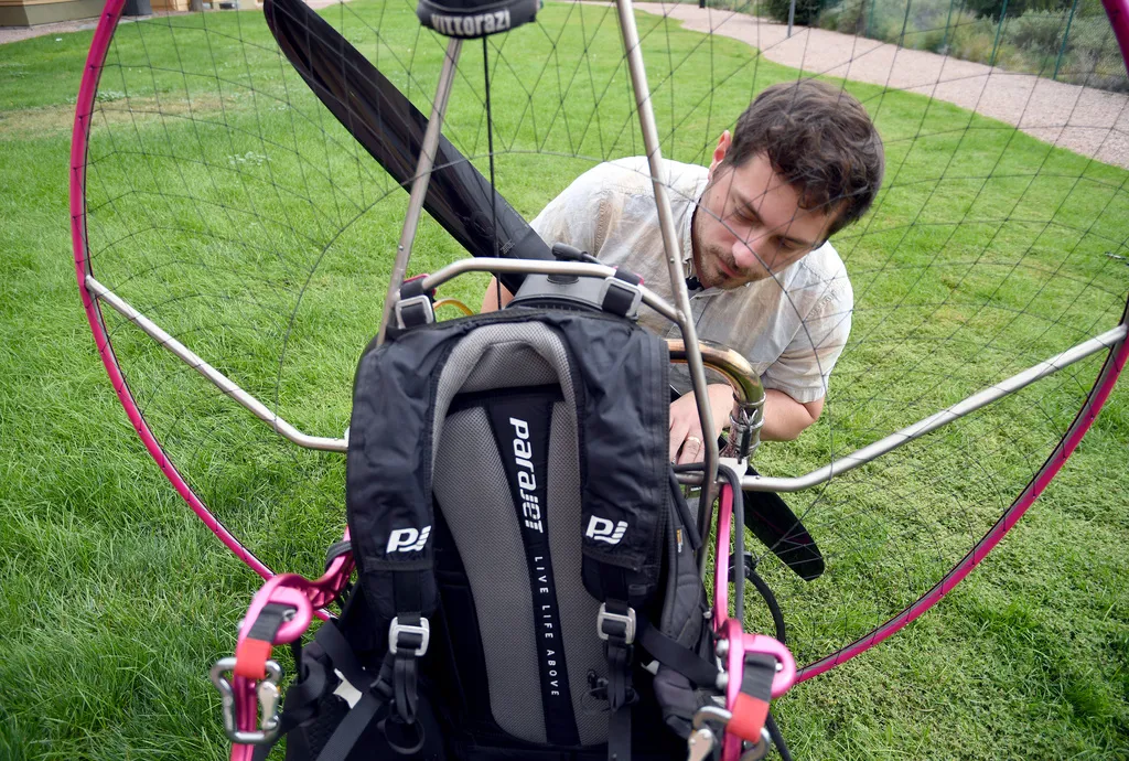 Jake Hutzler, who often flies to his air traffic controller job, inspects his paramotor outside his home in Pueblo, Colo.