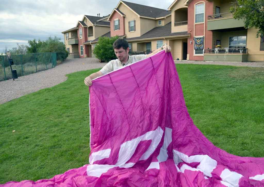 Jake Hutzler, who often flies to his air traffic controller job, shakes sand from his paramotor wing outside his home 