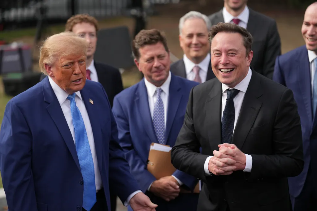 President Donald Trump listens as Elon Musk speaks to reporters at the White House