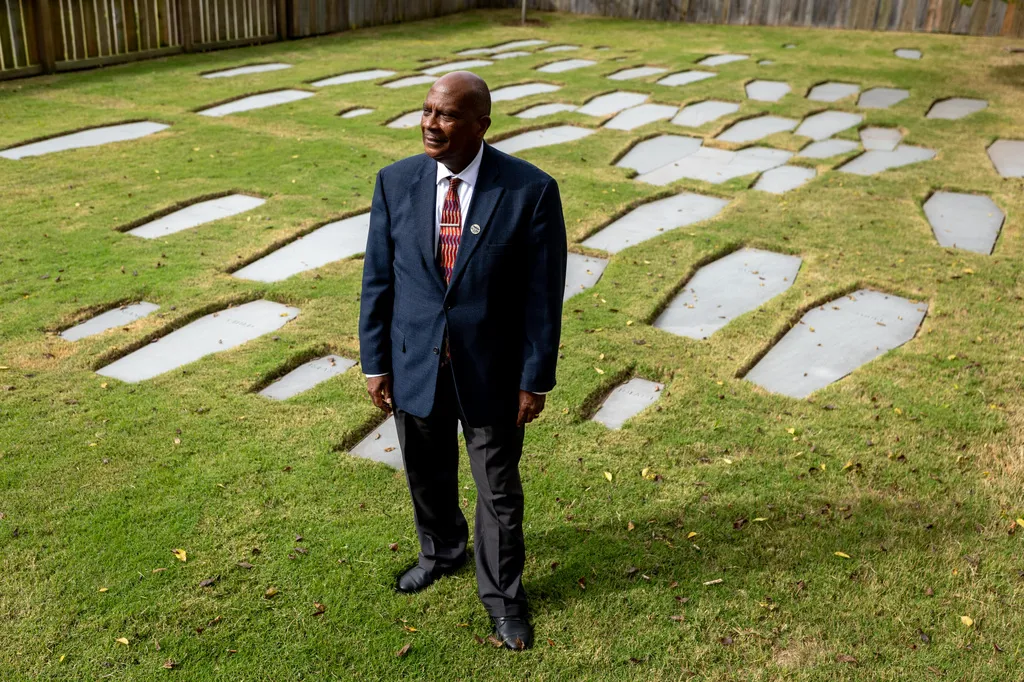 Reginald F. Davis, pastor of First Baptist, poses for a photo alongside the burial ground that sits just outside the reconstructed African Baptist Meeting House, now known as the First Baptist Church