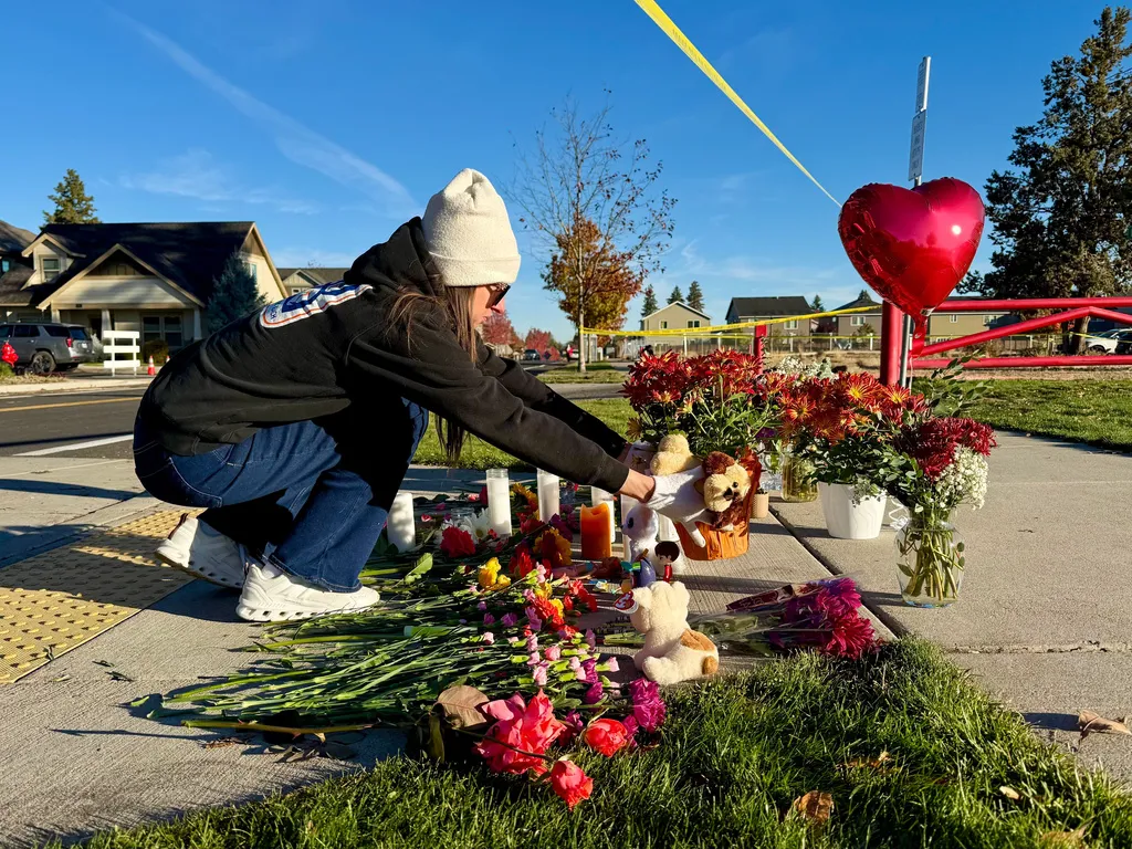 A person places flowers at a makeshift memorial on the other side of Silver Rail Elementary School in Bend, Ore.