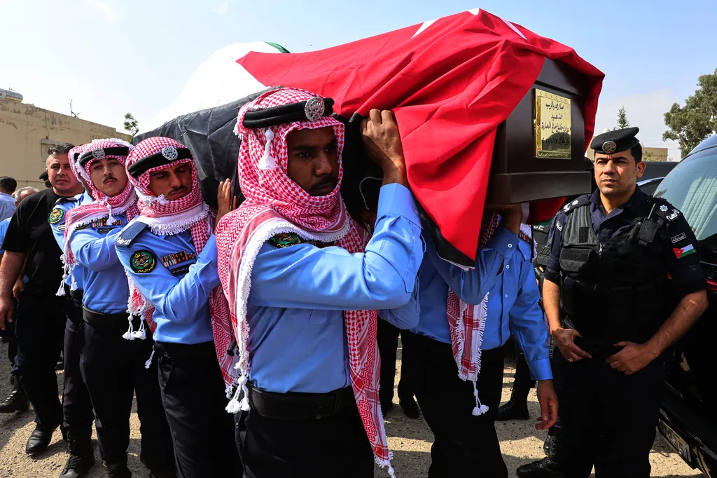 Jordanian honor guards carry a flag-draped coffin of on of the victims killed in an attack on a Greek Orthodox church