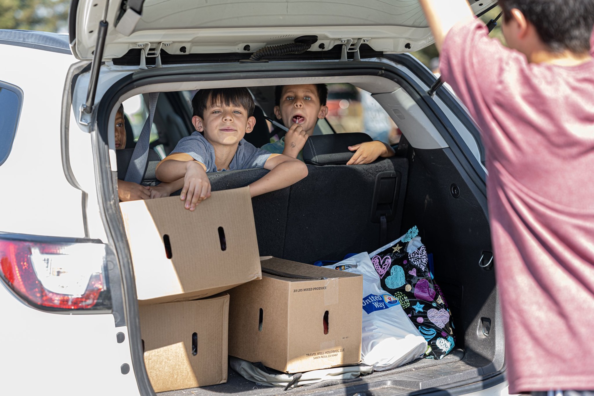 Kids in car receiving food boxes