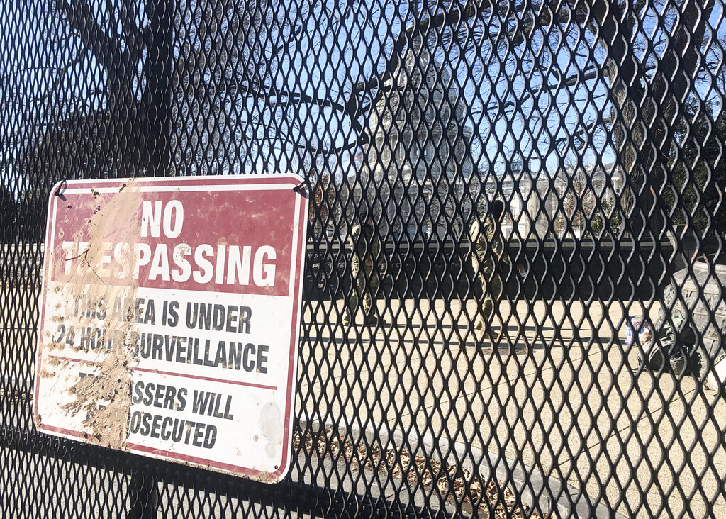 Members of the National Guard stand inside anti-scaling fencing that surrounds the Capitol complex