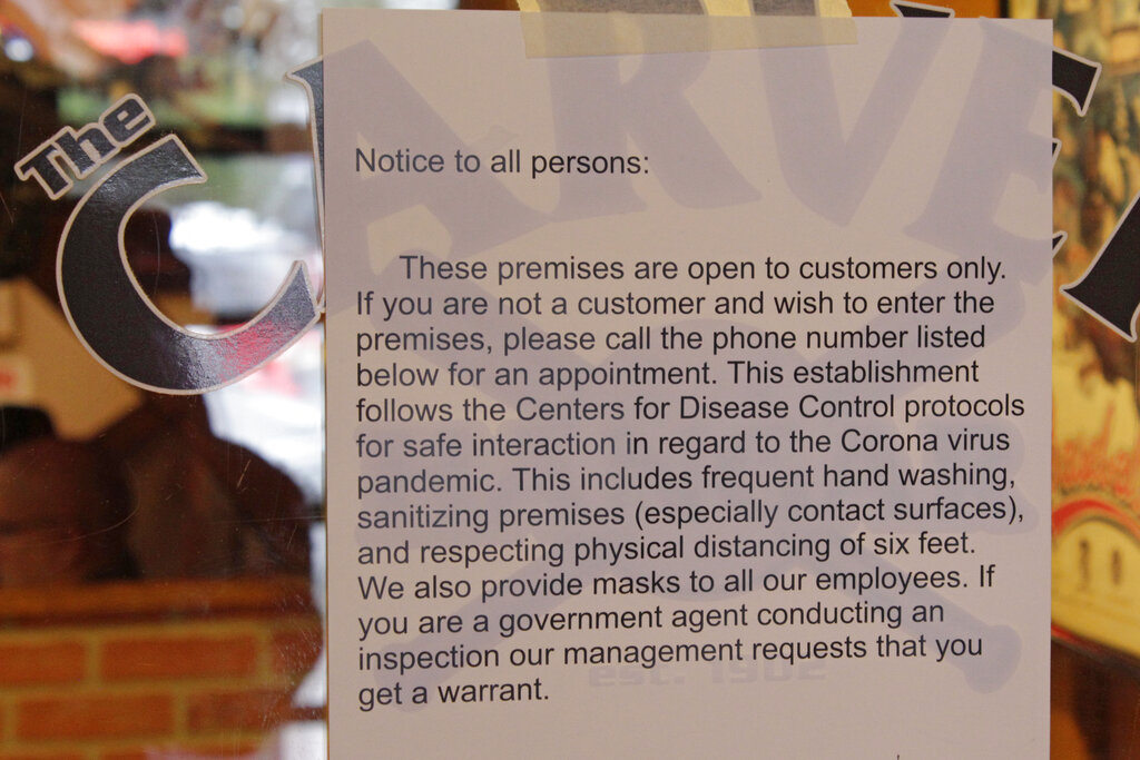 A sign telling state inspectors not to enter without a warrant hangs on the door of the Carver Hangar, a restaurant in Boring, Ore.