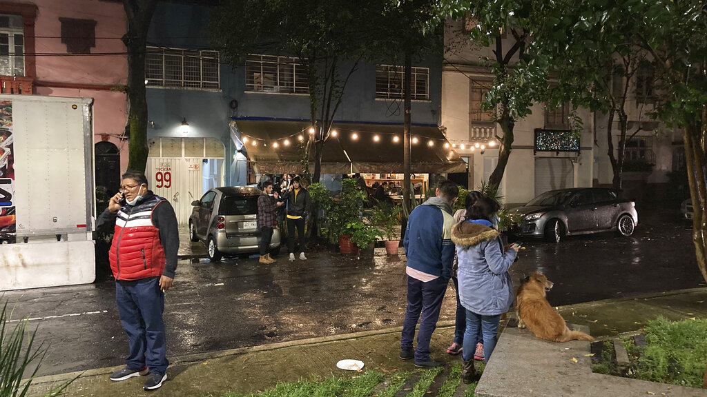People gather outside on the sidewalk after a strong earthquake was felt, in the Roma neighborhood of Mexico City