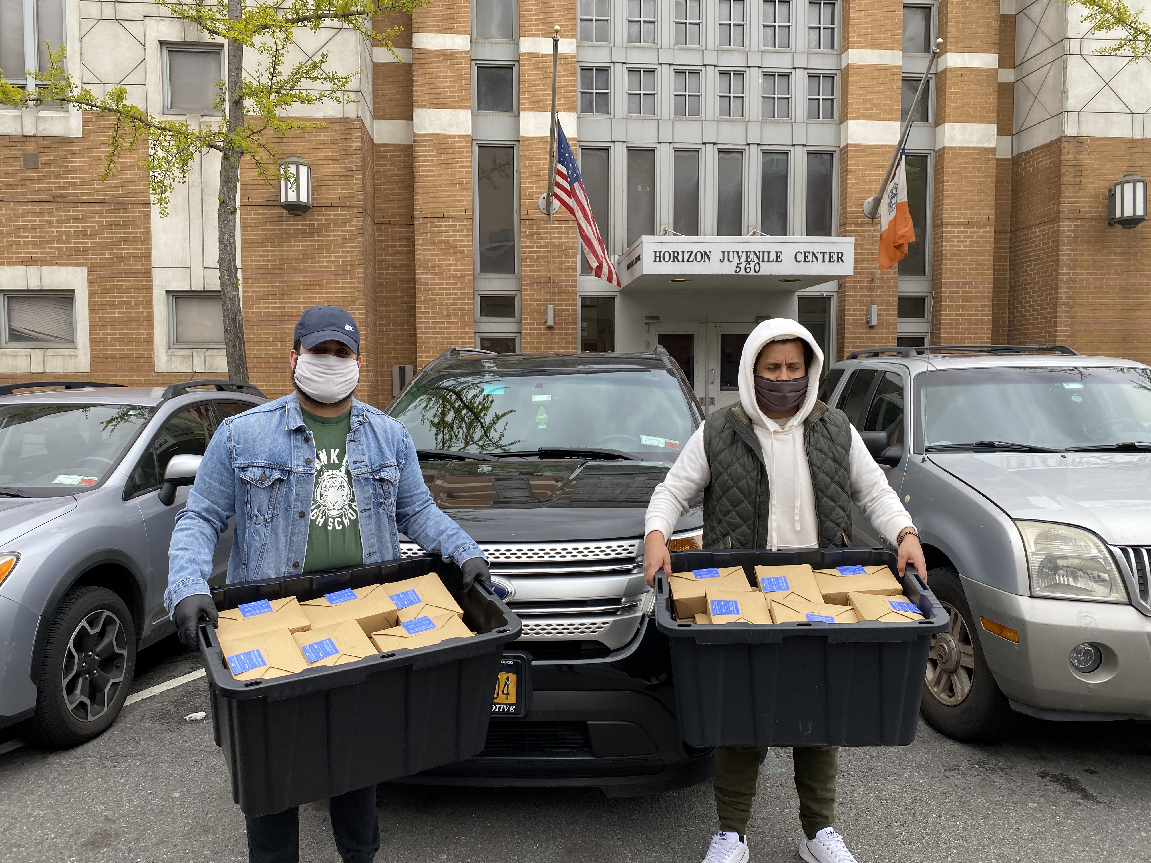 Two people holding tubs full of packaged meals