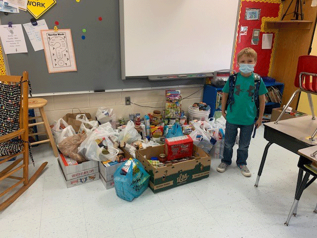Graeme at school with all the food collected by his class to help others, free-of-charge