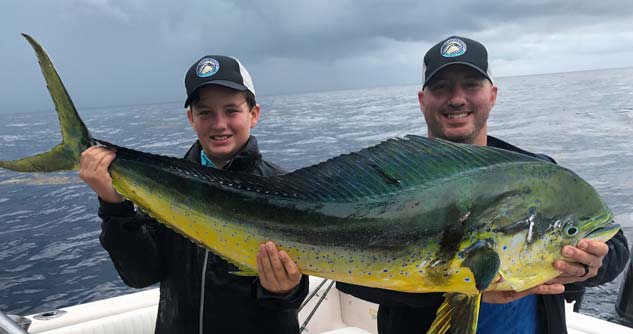 Boy and man hold up giant deep sea fish