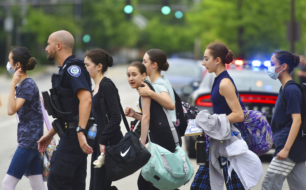 People are escorted away from the scene of a mass shooting at a Fourth of July parade in Highland Park, Ill.
