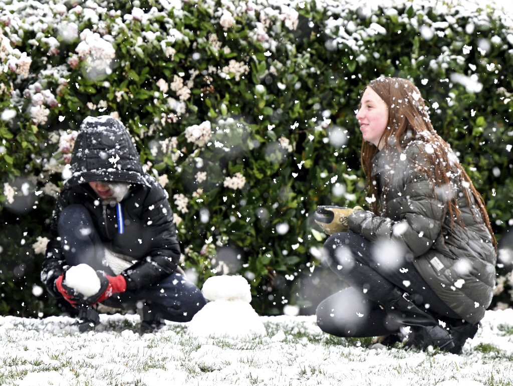 Brody Mielke, left, 10, and his older sister Braelynn, 12, make a snowman as snow falls at approximately the 1,700 foot level in front of their Fontana, Calif., home in Hunters Ridge 