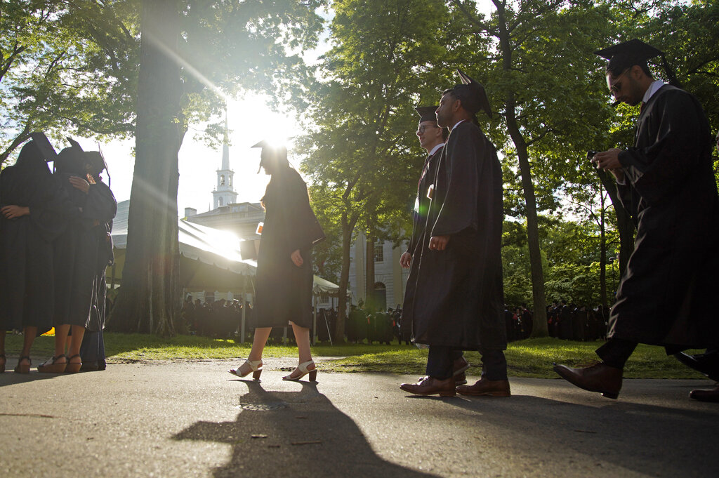 Graduates walk at a Harvard Commencement ceremony held for the classes in Cambridge, Mass.