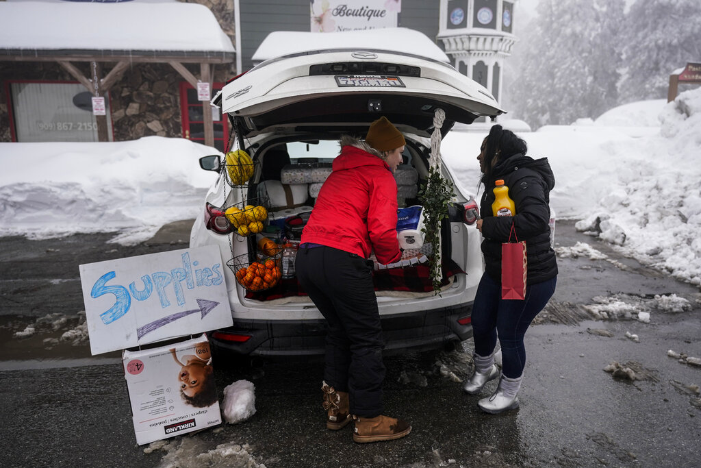 Ruth Aldama, center, who set up a makeshift supply shop on the road, talks to a resident in Running Springs , Calif.