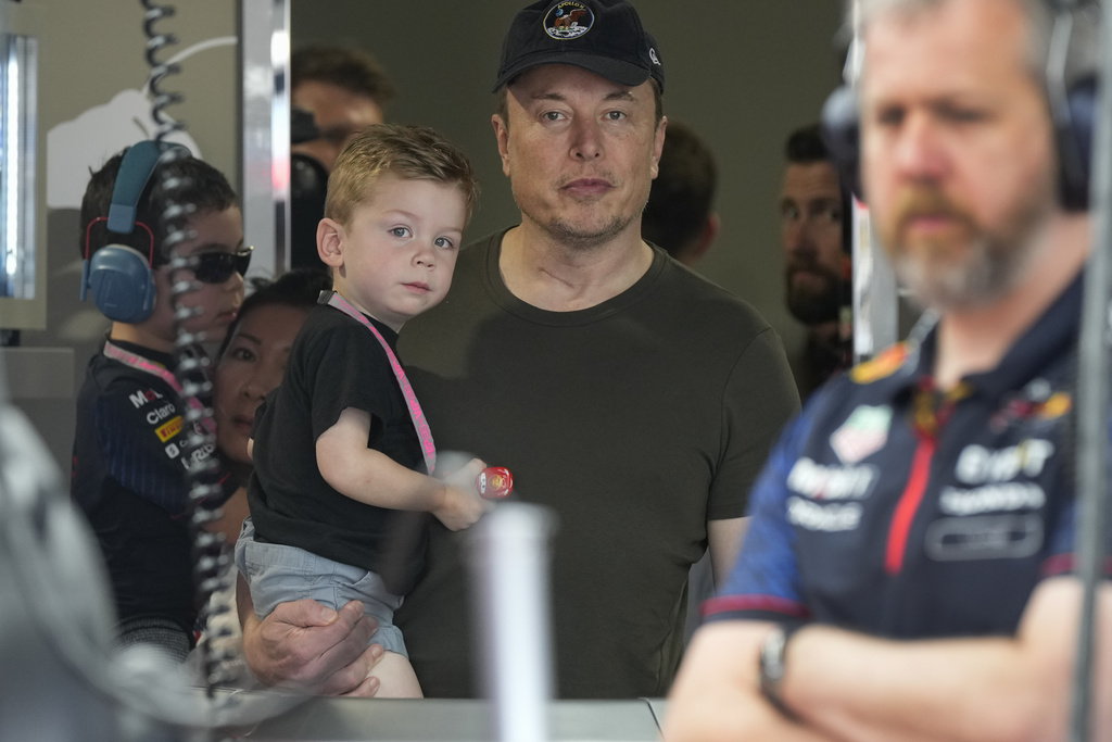 Elon Musk holds one of his children as he watches a Red Bull racing crew during practice for the Formula One Miami Grand Prix auto race, at Miami International Autodrome