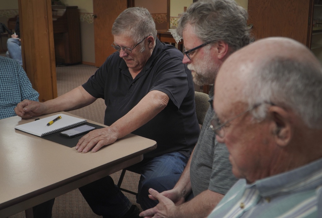 Crop farmer Bob Worth, left, prays with his pastor and fellow church council members at their weekly meeting in the basement of the Lake Benton United Methodist Church in Lake Benton, Minn.