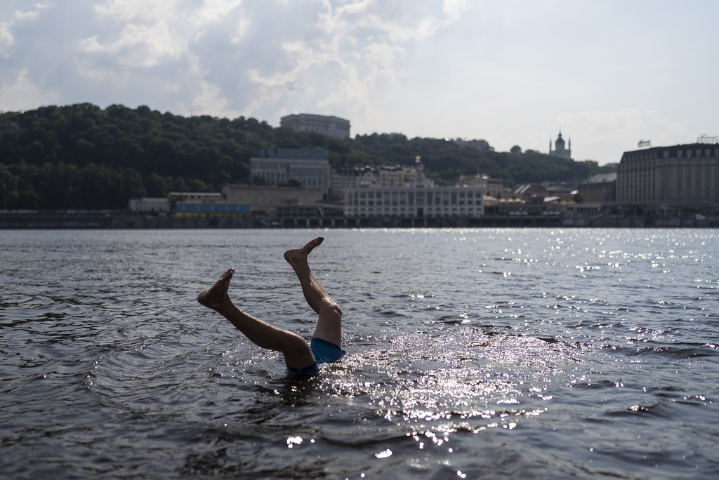 A man does a flip while cooling off in the Dnieper River in Kyiv, Ukraine