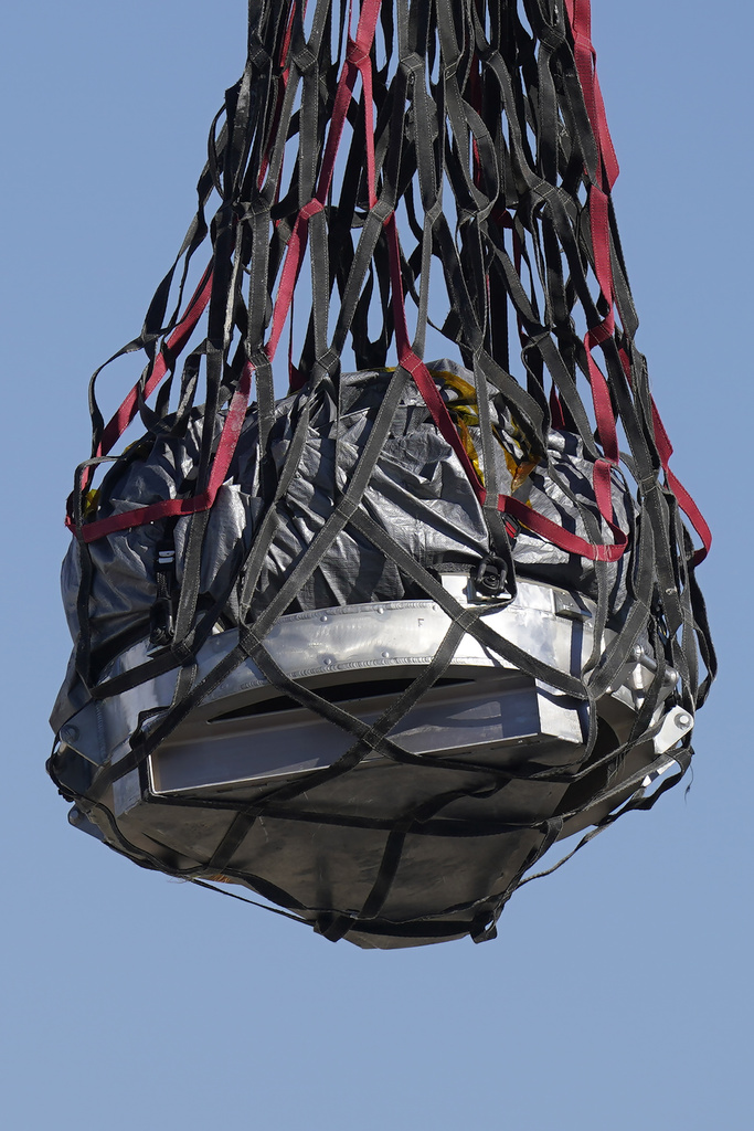 A helicopter delivers a space capsule carrying NASA