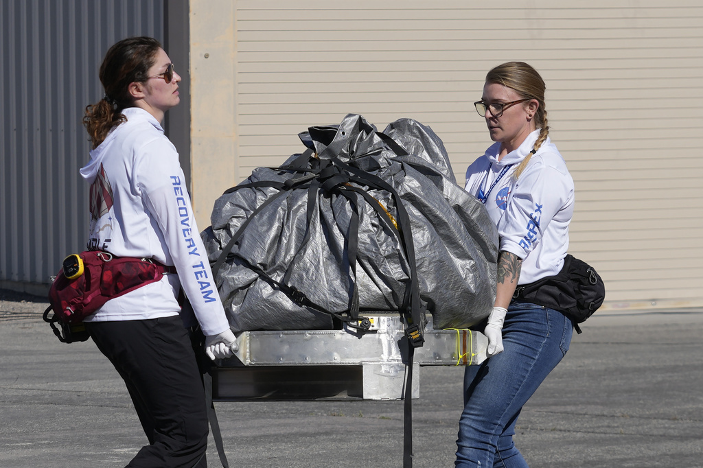 Recovery team members carry a capsule containing NASA