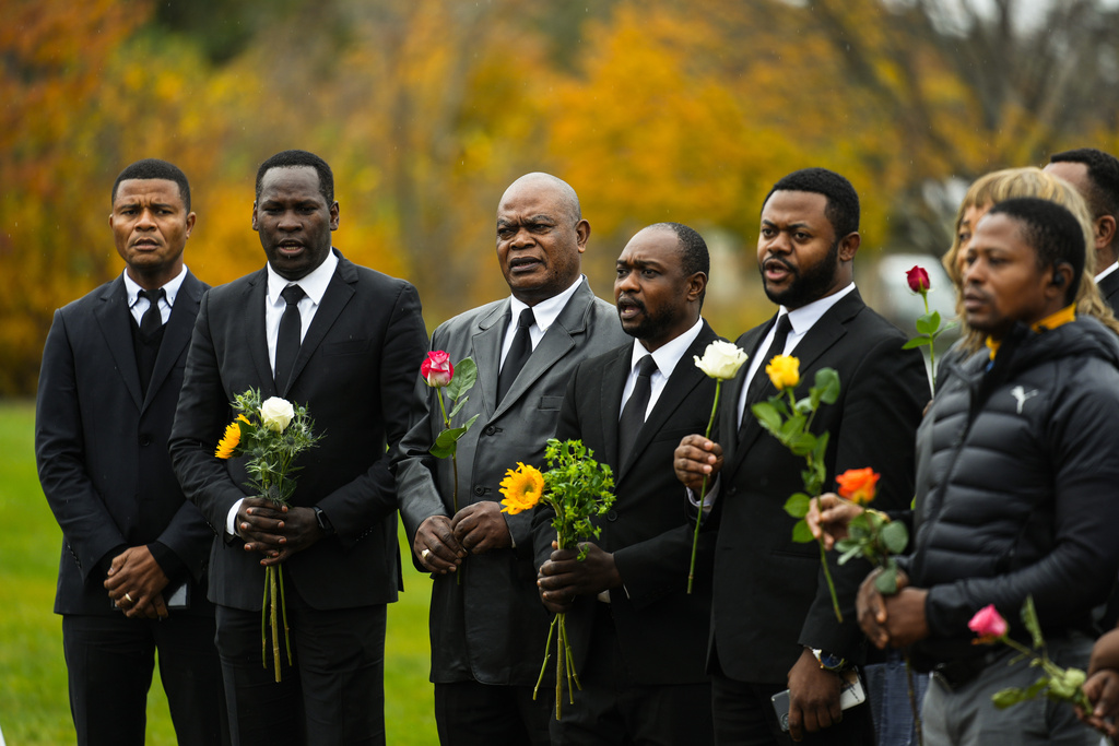 Members of the New Apostolic Church sing at a makeshift memorial outside a bowling alley, the site of one of this week