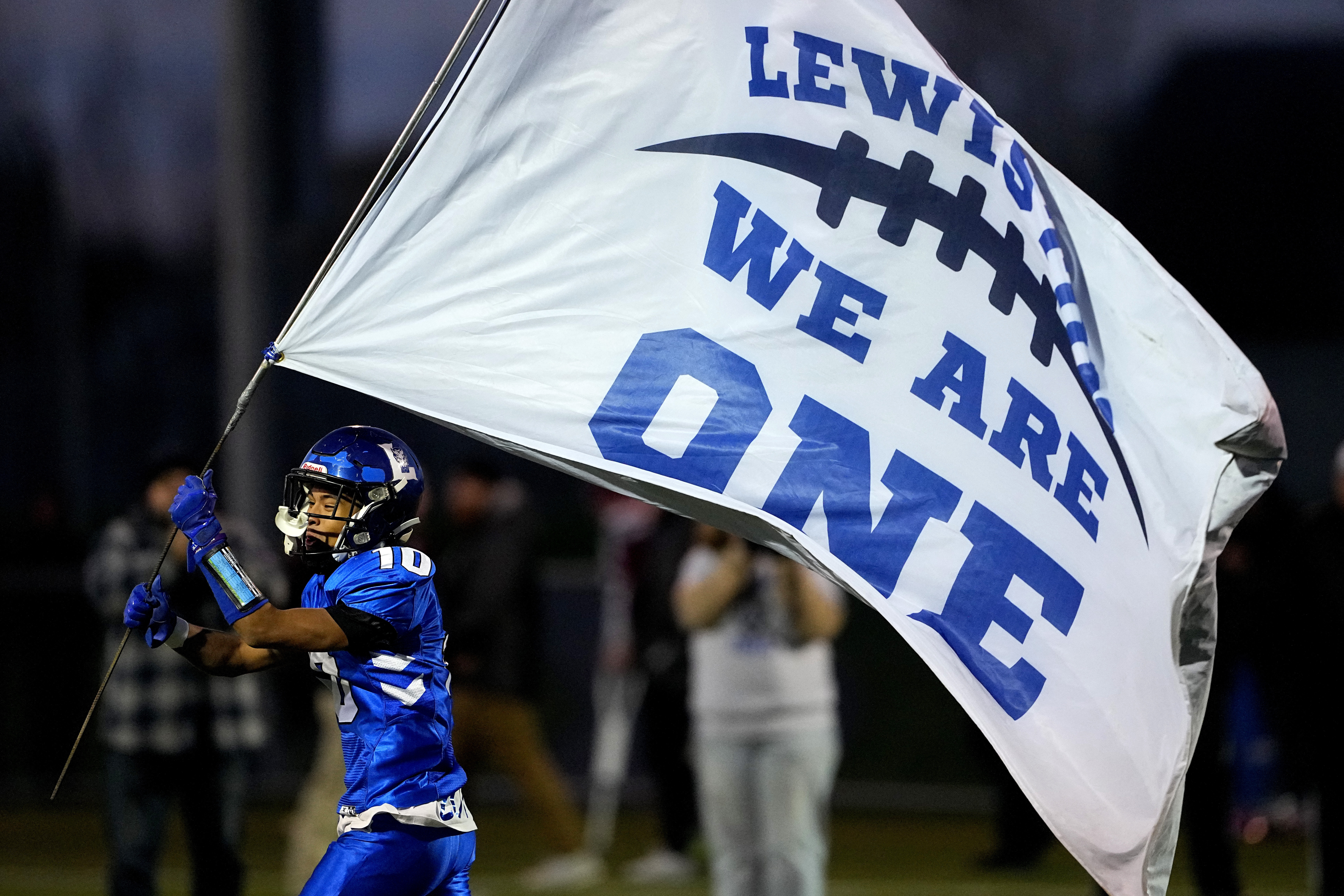 Lewiston High School running back Jayden Sands carries a flag onto the field prior to a football game against Edward Little High School, Wednesday, Nov. 1, 2023, in Lewiston, Maine. 