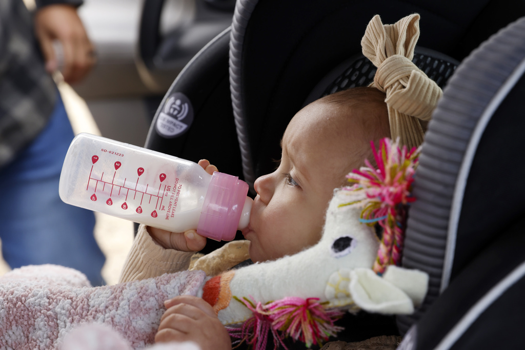 One-year-old Cora Dibert drinks from a bottle after being buckled into her car seat at The Bridge Church