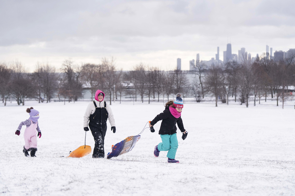 Kelly Schoenfelt, center, her daughter Quinlynn, left, 6, and Parker Melowsky, 7, run up Cricket Hill in the Uptwon neighborhood with sleds after a major snowstorm hit the Chicago area