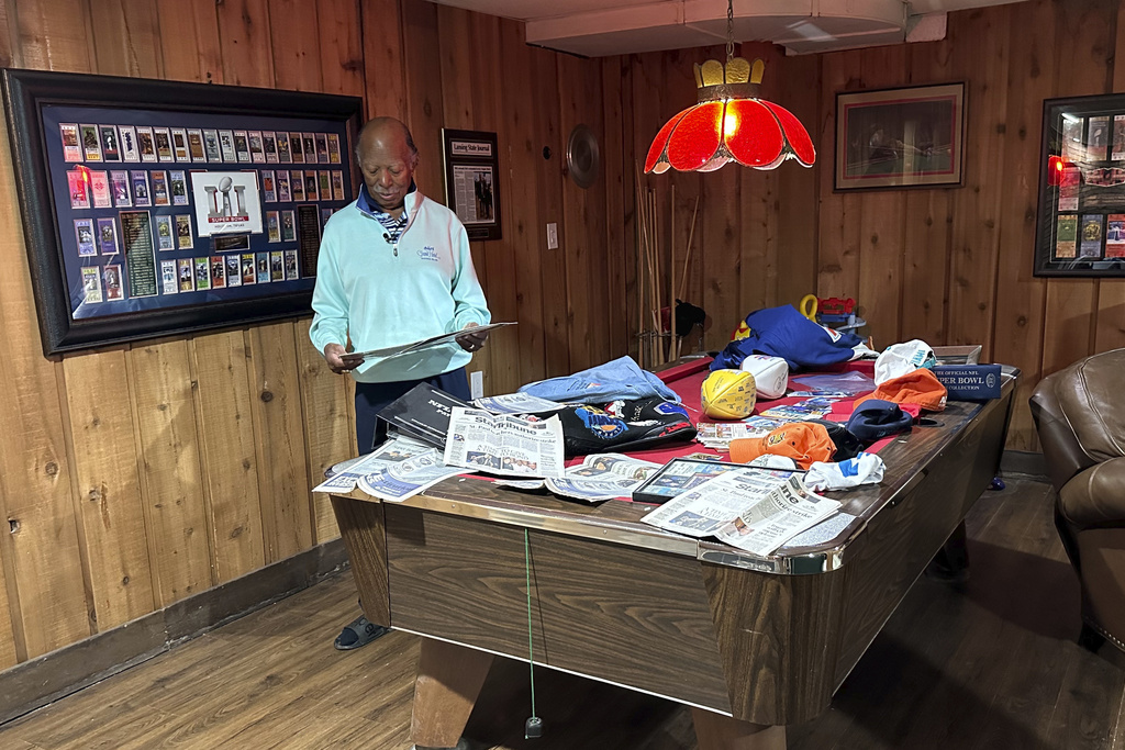 Gregory Eaton looks at some Super Bowl memorabilia at his home in Lansing, Mich.