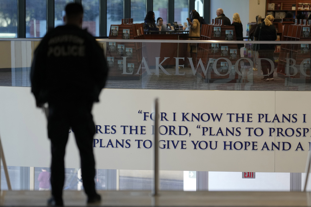 A police officer stands at the top of the steps inside Lakewood Church