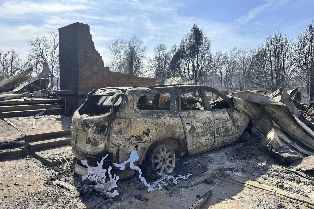 Burned car rests near the charred remains of a home outside of Canadian, Texas