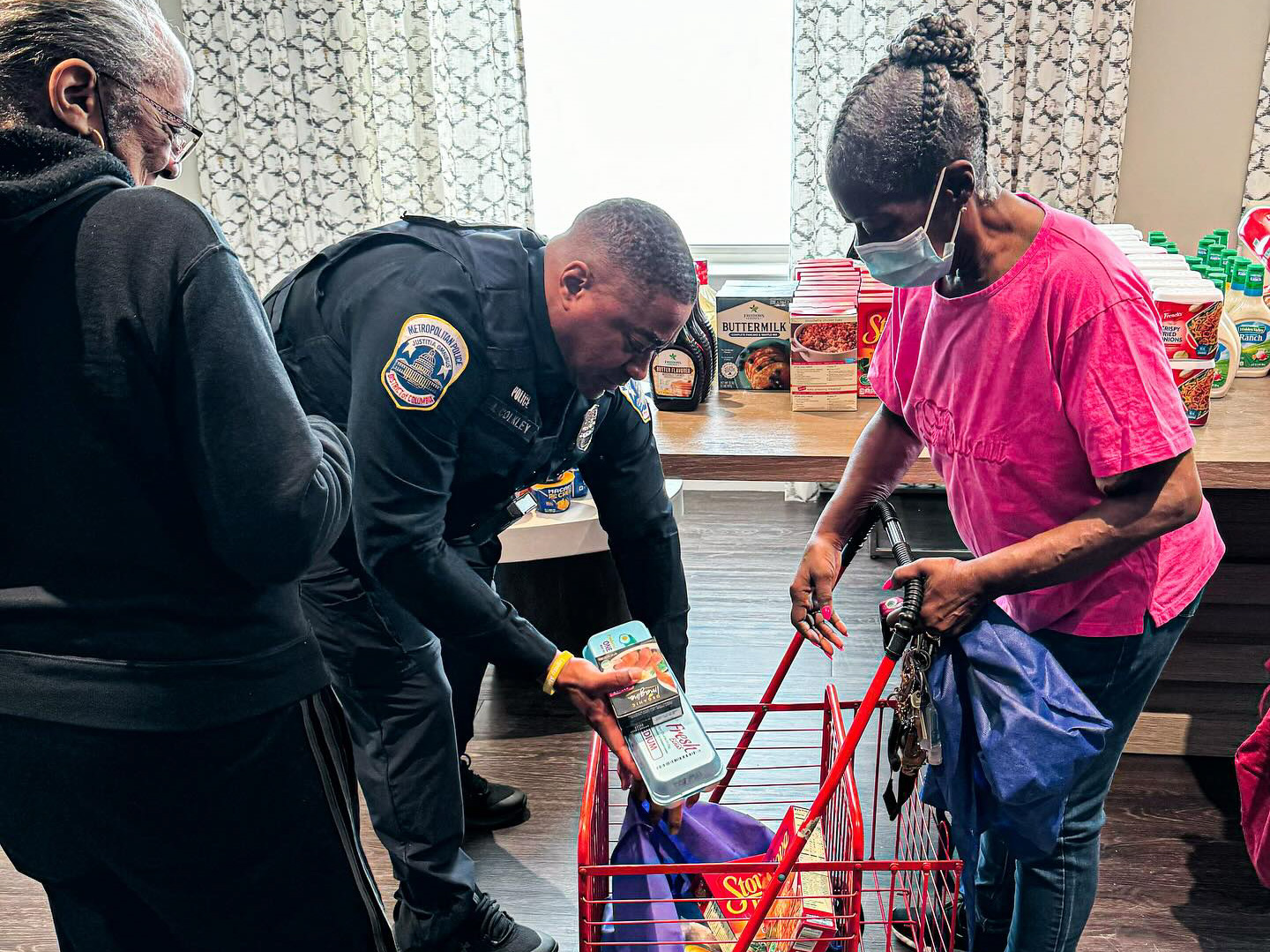 Officer in uniform bending over to put food in woman