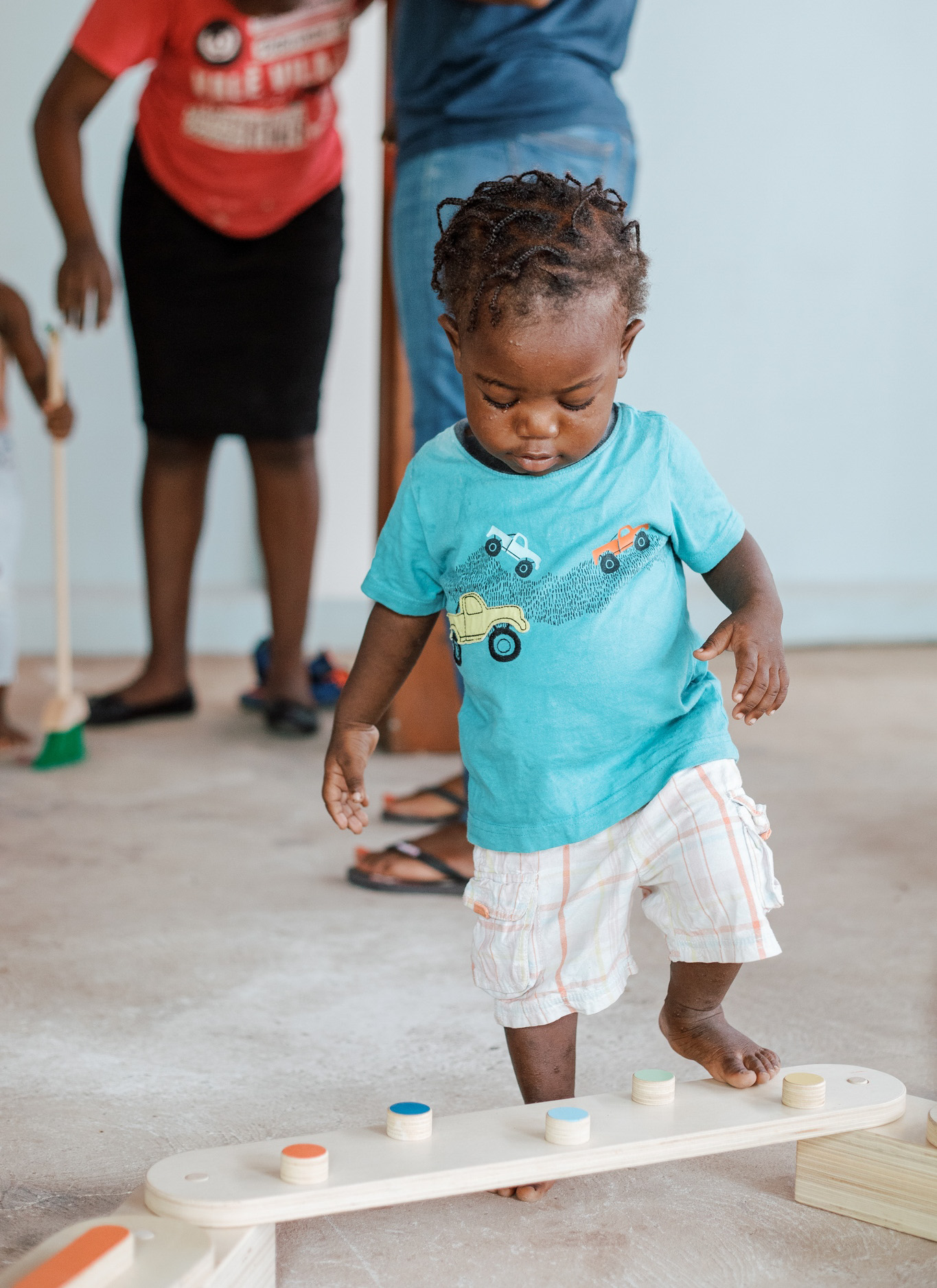 Toddler stepping up with adults in the background