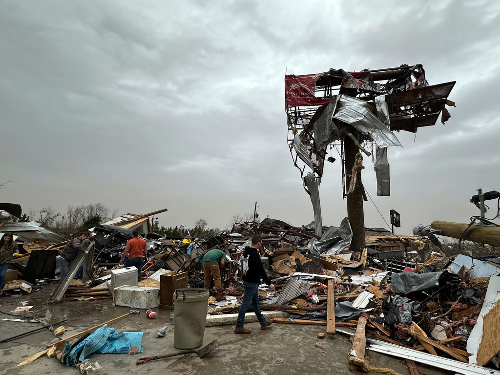 People work through the debris of the Cave City Auto Parts store after a severe weather storm in Cave City, Ark.